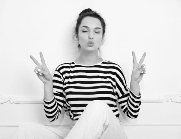 beautiful brunette woman girl model with nude makeup summer hipster clothes posing near wall sitting floor giving kiss showing peace sign - Tendencias de diseño web que dominarán las pantallas en 2026: Guía para marcas que buscan el futuro