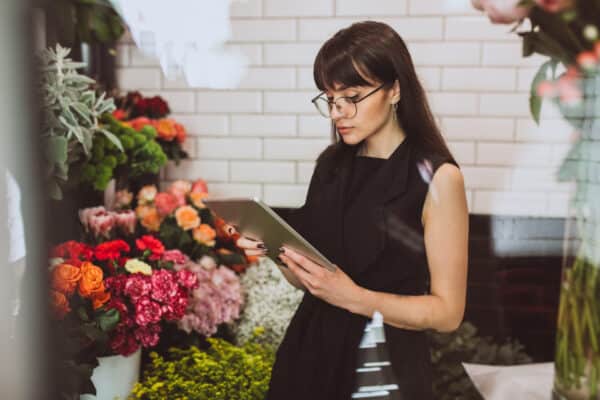 woman florist her own floral shop taking care flowers - Atención al cliente por WhatsApp Automatizada: El Secreto Definitivo para Vender 24/7 (Sin Ser Esclavo del Celular)
